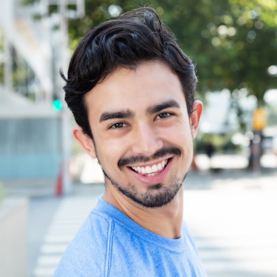 Hispanic guy in the city looking at camera outdoor in the city with buildings in the background