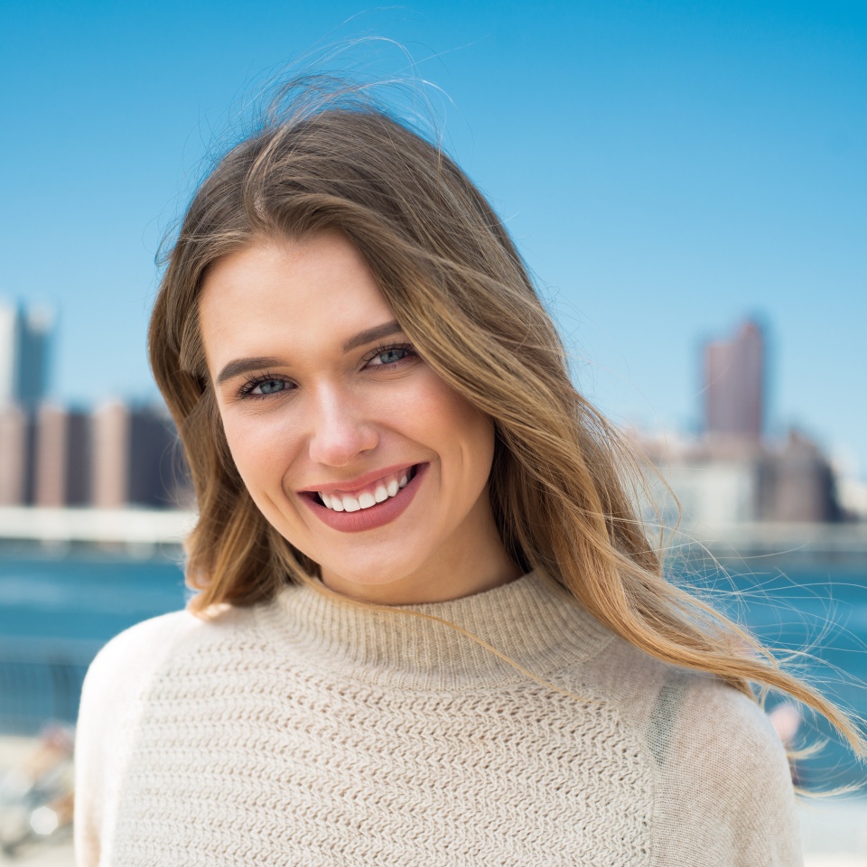 Close-up portrait of beautiful young woman with perfect natural white teeth smile at sunny day
