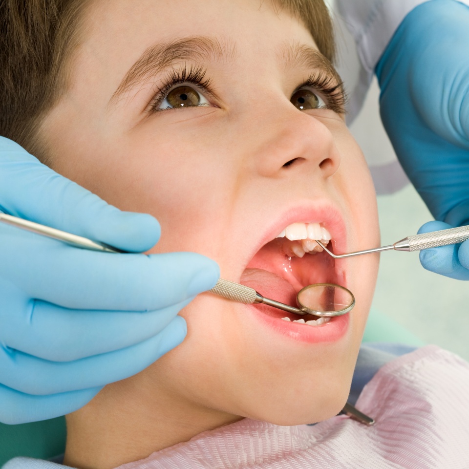Close-up of little boy opening his mouth wide during inspection of oral cavity
