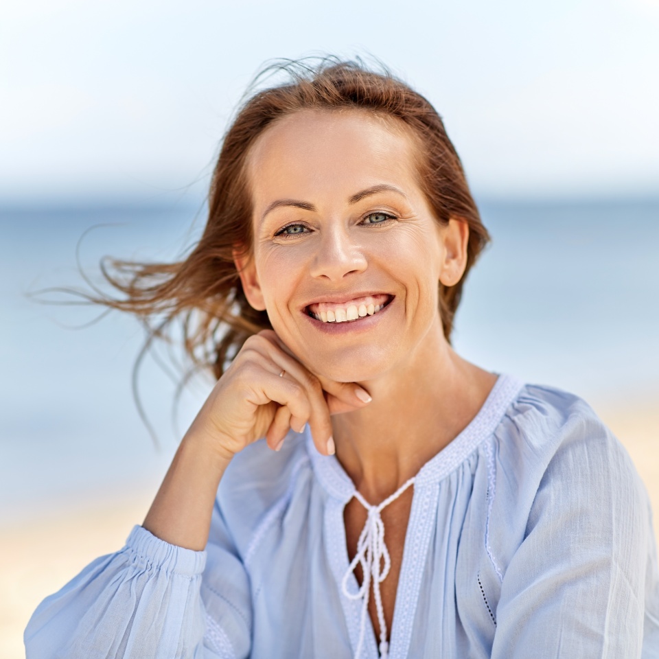 people and leisure concept - portrait of happy smiling woman on summer beach