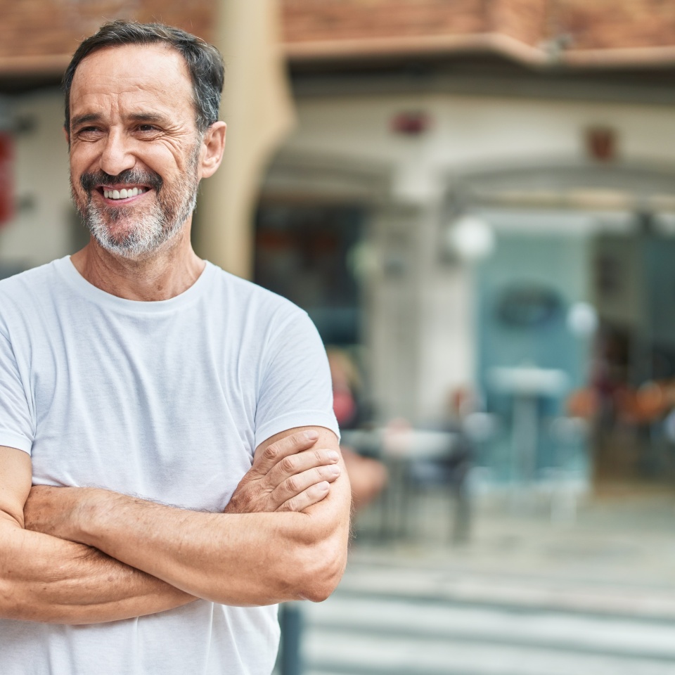 Middle age man standing with arms crossed gesture at street