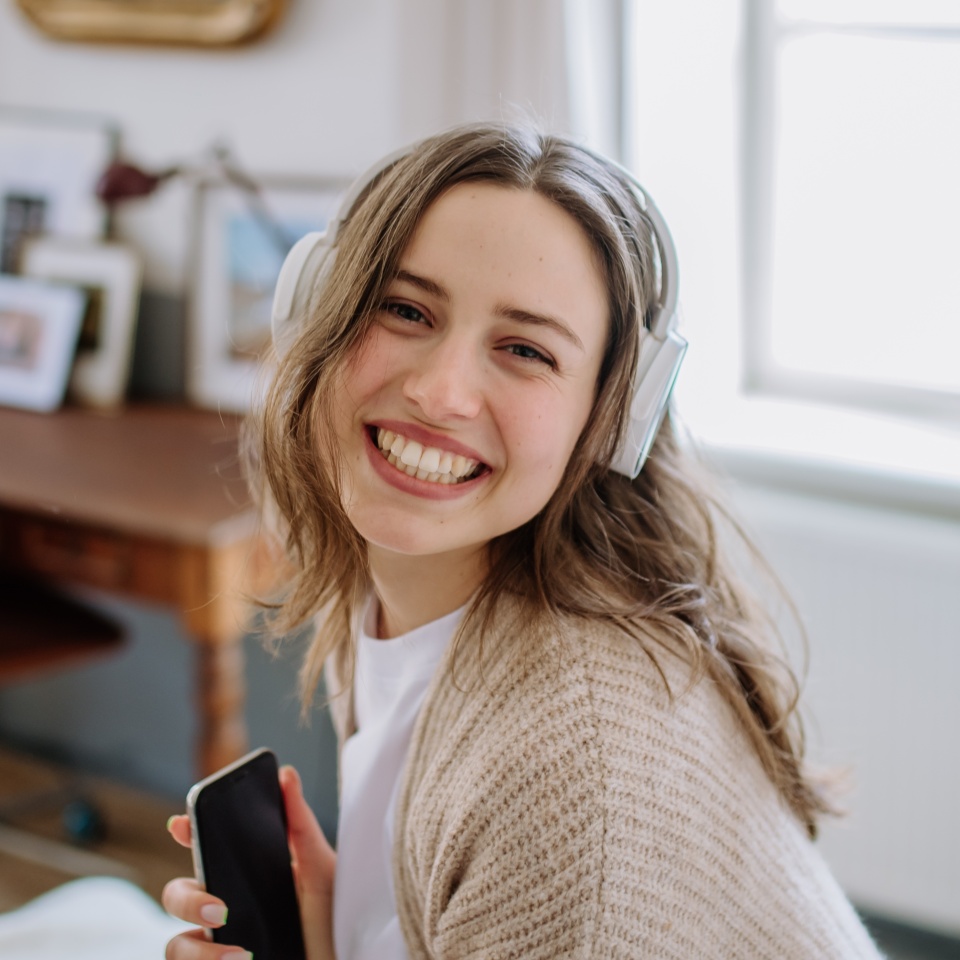 Young woman listening music trough headphones in her apartment.