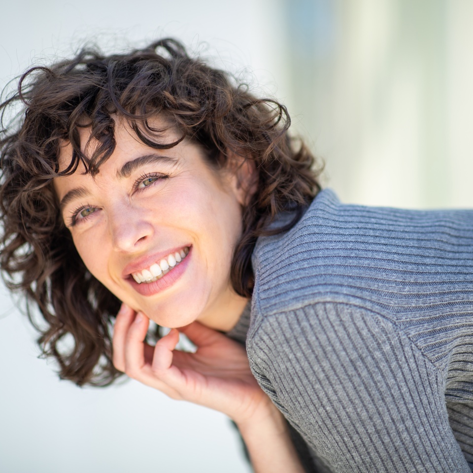 Close-up portrait of pretty young woman looking at camera and smiling outside