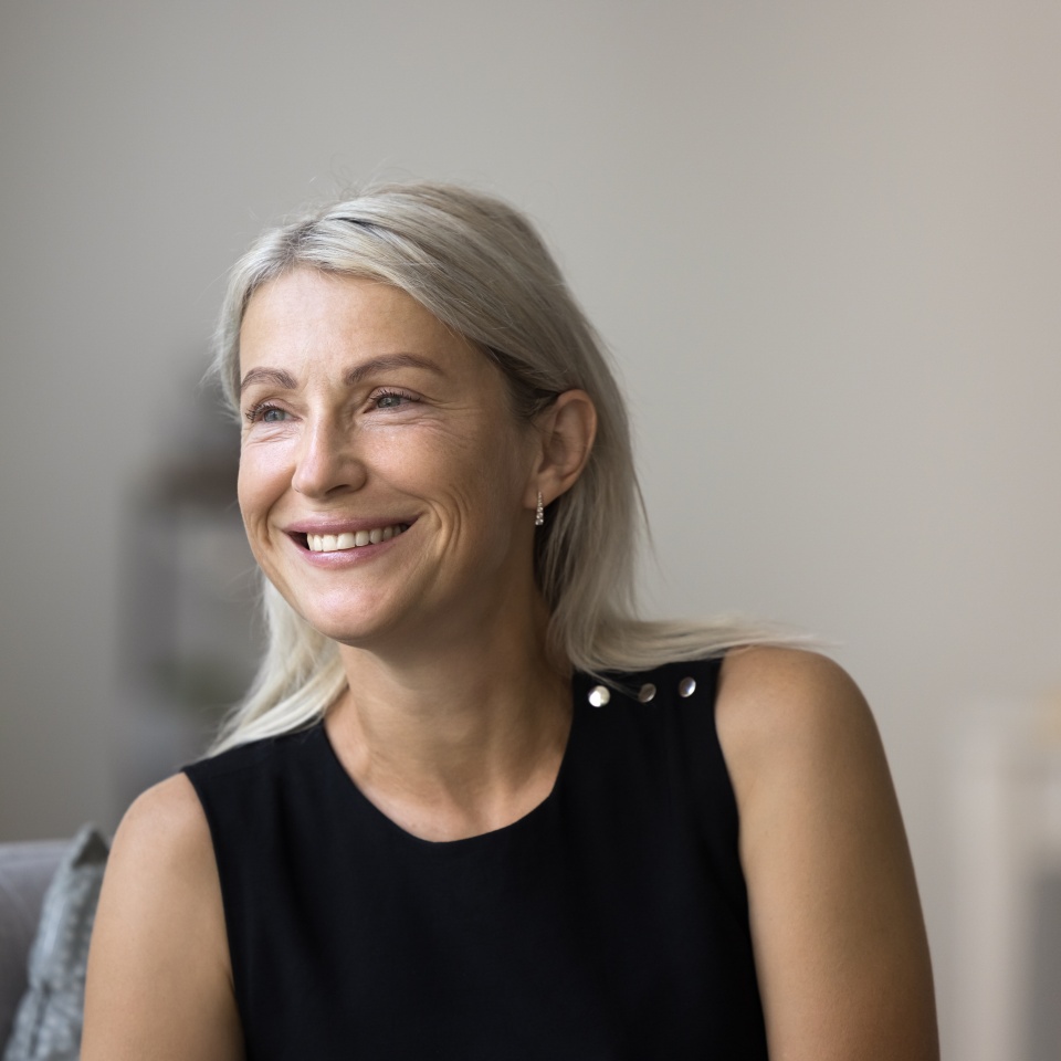 Attractive good-looking middle-aged woman spend time at home sit on armchair staring into distance deep in pleasant thoughts and aspirations, planning bright future at new own apartment. Leisure, rest