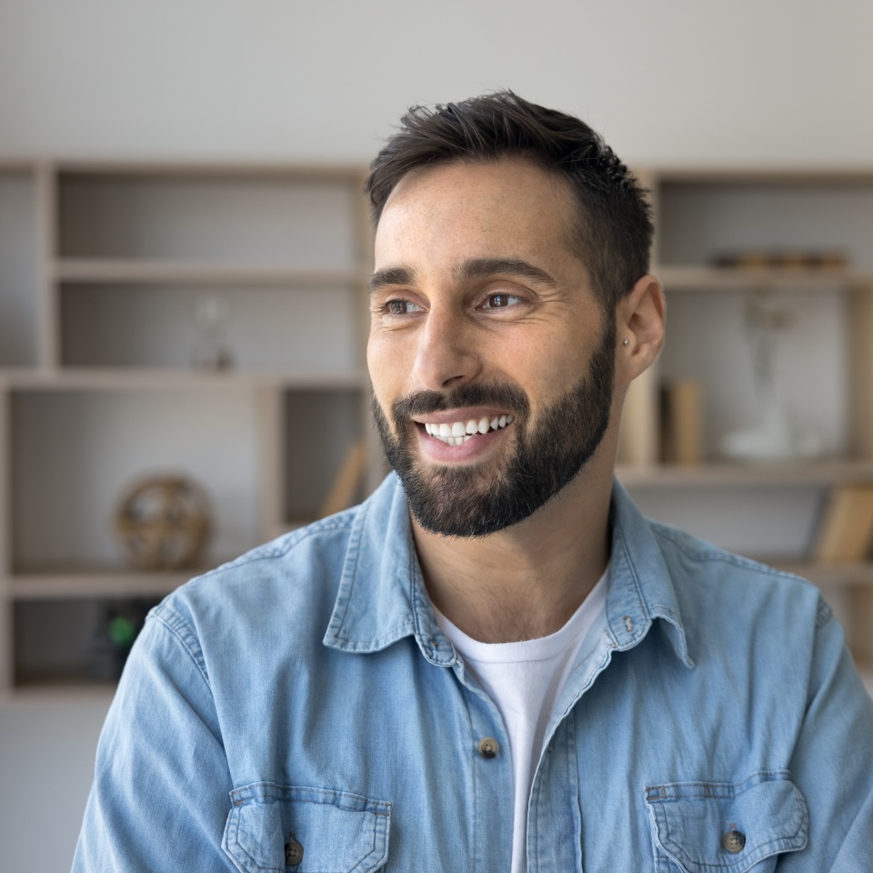 Happy handsome Latin man in casual looking at window away with toothy smile, thinking on career success, successful startup, creative work ideas, dreaming on future income. Male casual portrait
